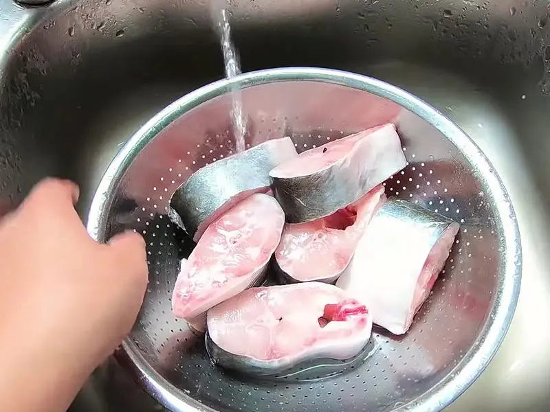 Sơ chế cá tươi ướp gia vị trong tô.